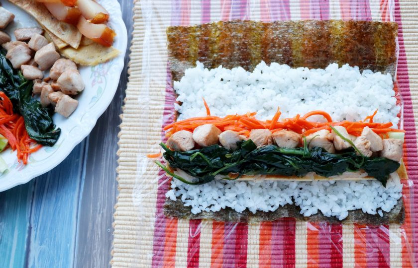 1. Этап. Кимбап: На лист нори выложите рис, удобно это делать слегка влажными руками. На рис положите омлет, морковь, дайкон, огурец, шпинат, кусочки мяса. Аккуратно сверните плотный ролл. В следующий ролл вместо мяса положите рыбу. Третий ролл приготовьте без мяса и рыбы, он будет вегетарианским.