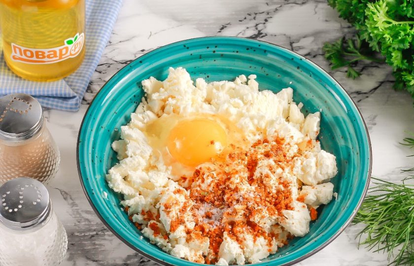 1. Этап. Несладкие сырники: Творог любой жирности выложите в глубокую емкость. Вбейте туда же куриное яйцо, всыпьте соль и приправу для мяса.