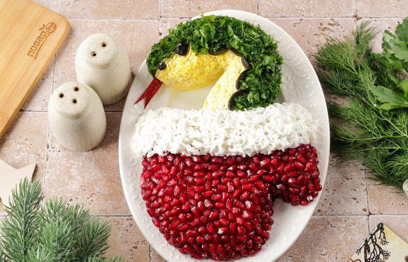 1. Этап. Новогодний салат Варежка на год Змеи: Змейку украсьте при помощи тёртого на мелкой тёрке желтка и мелко рубленной зелени. Из нарезанных маслин можно выложить контур змейки, сделать глаз и носик. Язык я вырезала из корки граната. Новогодний салат 