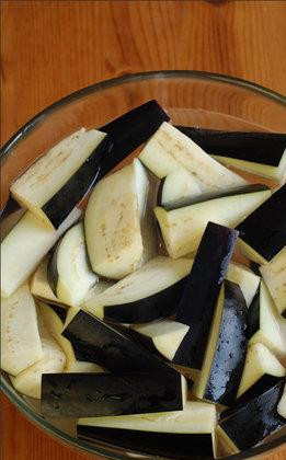 1. Этап. Баклажаны по-пекински: Нарезаем наш баклажан продольными ломтиками длиной где-то в 5 см, как показано на фотографии. ОЧЕНЬ ВАЖНО - нарезанный баклажан замачиваем в обыкновенной холодной воде на 10 минут. Благодаря этому баклажан не впитает в себя масло при жарке. Пока баклажан замачивается, мелко нарезаем зеленый лук и кинзу.