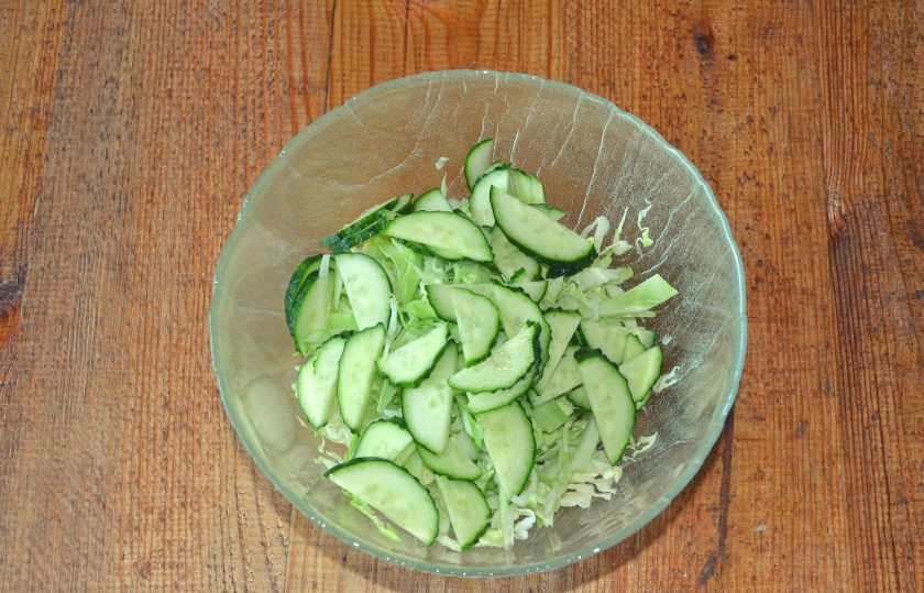 1. Этап. Салат с капустой, огурцами и кукурузой: Тонкими ломтиками нарежьте огурец.