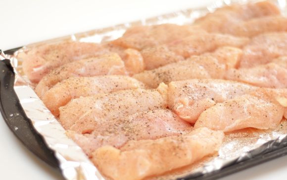 1. Этап. Куриная грудка в сметане: 3. На дно противня или формы для запекания выложить пергамент или фольгу. Слегка смазать сливочным маслом и выложить ровным слоем курочку. Слегка поперчить и при желании посолить (важно помнить, что соус уже соленый). Можно добавить специи для курицы или другие любимые приправы.