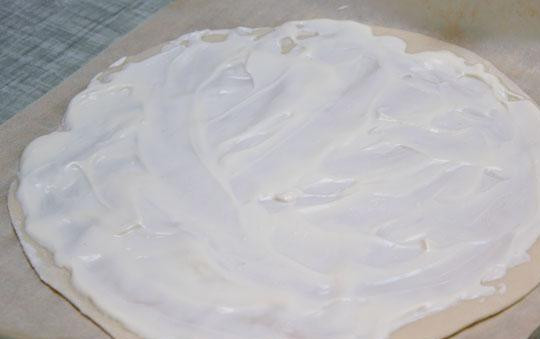 1. Этап. Фламмкухен: Каждую часть раскатать в тонкую лепешку, уложить на бумагу для выпекания и равномерно смазать жирной сметаной.