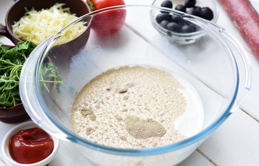 1. Этап. Пицца на сухом молоке: В просторную миску залейте молочную смесь, добавьте сахар, сухие дрожжи. Перемешайте все.