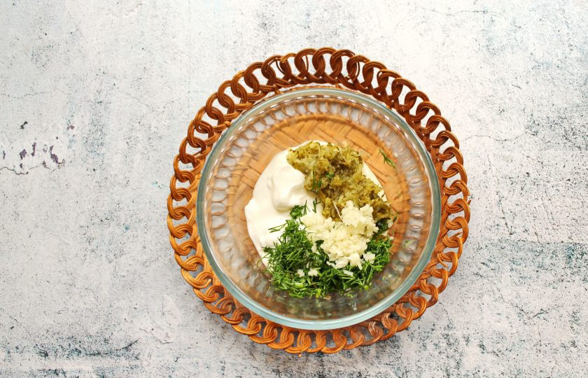 1. Этап. Минтай в сметане с маринованными огурцами: В миску выложите сметану, огурцы натертые на средней терке, мелко нарезанный укроп и перемешайте.