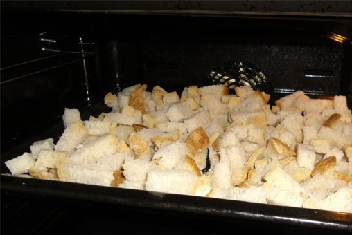 1. Этап. Гренки с чесноком в духовке: Затем выкладываем нарезанный хлеб на противень и ставим в духовку. Устанавливаем температуру 180-200 градусов и запекаем, пока хлеб не подсохнет и не станет золотистого цвета. Время от времени его нужно перемешивать и поднимать нижние кусочки наверх.