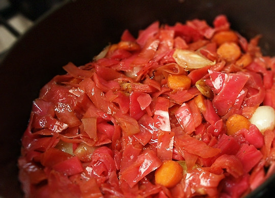 1. Этап. Гусь, тушенный с капустой: Квашеную розовую капусту нарежьте крупными кусками, промойте под водой, после чего слейте лишнюю жидкость. Нарежьте мелкими кусочками и добавьте в казан к овощам, перемешайте.