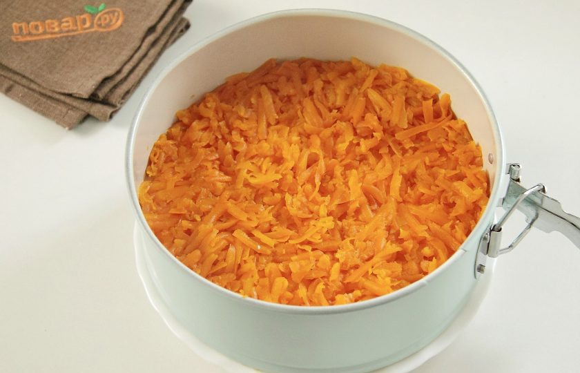 1. Этап. Мимоза на Новый год в виде свинки: На тертые белки положите слой моркови, разровняйте ее и смажьте майонезом.