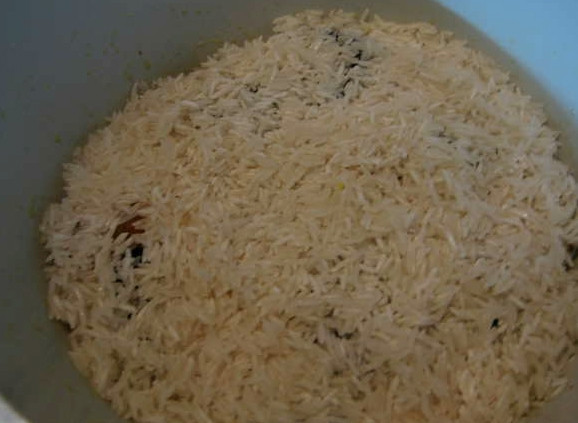 1. Этап. Плов с тыквой и сухофруктами: Если вы собрались варить рис или делать плов, то обязательно промойте рис под проточной водой до прозрачной воды. После этого замочите его в холодной воде хотя бы на полчаса. После этого можно из него готовить. Выкладываем промытый рис поверх тыквы с сухофруктами, распределяя его равномерно.