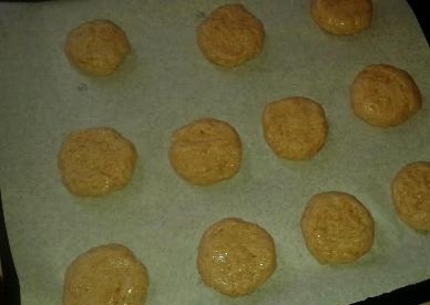 1. Этап. Постное яблочное печенье: Противень застилаем пергаментом, смазываем руки растительным маслом и ложкой набираем тесто. Скатываем из теста шарик и выкладываем на пергамент, а затем придавливаем, формируем печенье толщиной около 1 см.