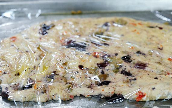 1. Этап. Фокачча с маслинами: 5. Разделить тесто пополам и из каждой половины раскатать большой тонкий овал или прямоугольник. Поместить тесто на отдельных противнях, смазанных оливковым маслом. Полить тесто сверху оливковым маслом и накрыть полиэтиленовой пленкой. Положить в теплое место на 1 час.