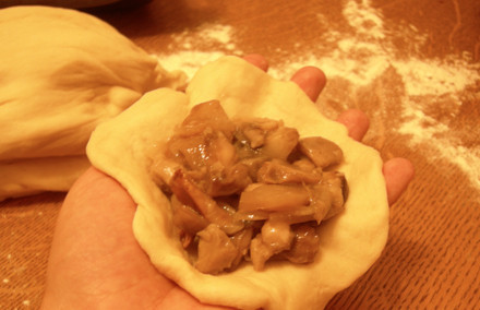 1. Этап. Пирожки с грибами в духовке: Когда тесто поднимется второй раз, опять его обминаем и приступаем к лепке пирожков. Отрываем от теста небольшой кусочек и раскатываем его в тонкую лепешку. В середину кладем начинку (1-2 столовые ложки), края плотно соединяем, то же самое повторяем с остальным тестом.