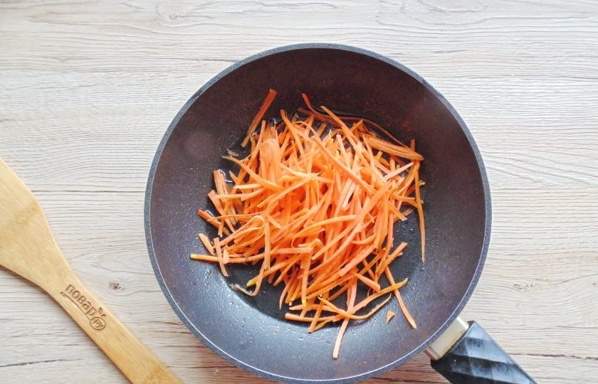 1. Этап. Фунчоза с древесными грибами: Морковь очистите, ополосните и натрите на тёрке для корейской моркови. Переложите в сковороду.