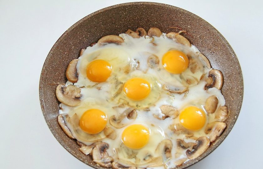 1. Этап. Яичница с грибами: 5. Слегка раздвиньте грибы с луком в стороны и разбейте на сковороду яйца. Посолите яйца по вкусу, по желанию можно добавить любимые специи.