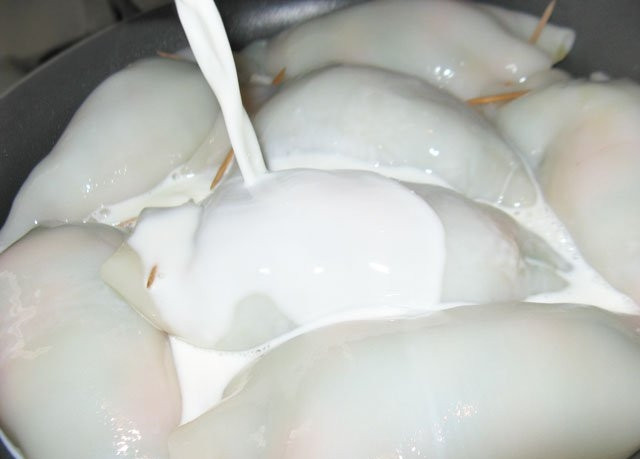 1. Этап. Кальмары, фаршированные овощами: 5. Готовые тушки выложите в сотейник или сковороду с высокими бортами. В сливки добавьте щепотку соли и перца, также можете использовать ароматные травы или специи по вкусу. Вылейте сливки в сотейник. Доведите до кипения, уберите огонь и тушите около 15-25 минут (в зависимости от размера тушек).