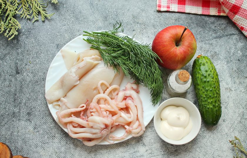 1. Этап. Салат с огурцом, кальмаром и яблоком: Подготовьте все необходимые ингредиенты для приготовления салата с огурцом, кальмаром и яблоком. В кастрюлю налейте воду, посолите и доведите до кипения. Опустите обработанные кальмары и щупальцы, доведите до кипения. Варите морепродукты в течение одной минуты, откиньте на сито и промойте их холодной водой, чтобы остановить процесс приготовления, остудите. Огурец и яблоко вымойте и обсушите.