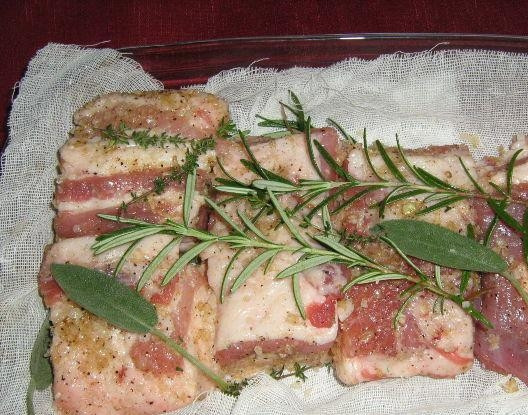 1. Этап. Сало в марле: На дно формы выложите марлю. На неё разложите несколько веточек тимьяна, лавровый лист, розмарин и шалфей. Сало натрите смесью из прошлого шага и положите сверху. И ещё добавьте веточки зелени.