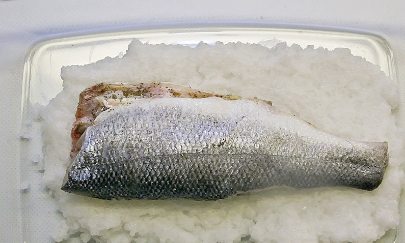 1. Этап. Сибас в соли: 4. В форму для запекания рыбы выкладываю на дно половину подготовленного ранее солевого панциря. На солевую смесь выкладываю потрошенную и смазанную специями рыбку.