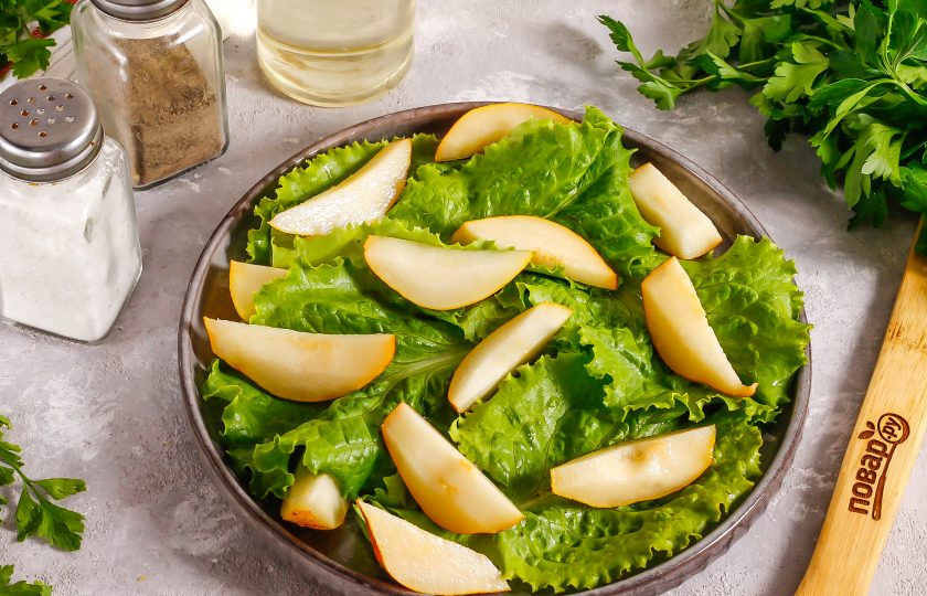 1. Этап. Салат с грушей и беконом: Груши промойте в воде, разрежьте пополам и вырежьте семена. Нарежьте мякоть ломтиками и выложите на листья салата.