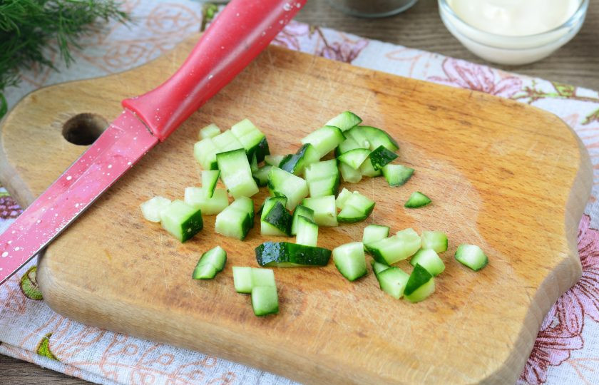 1. Этап. Салат с ветчиной и плавленым сыром: Срежьте хвостики с огурцов. Нарежьте овощи также средними кубиками.
