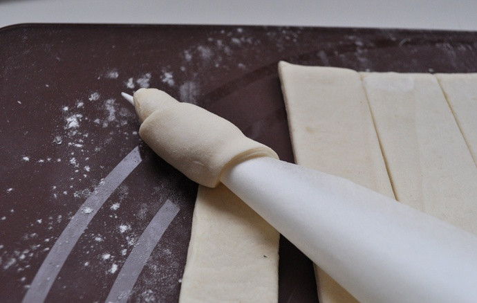 1. Этап. Слоеные трубочки: Берем первую полоску из теста и аккуратно наматываем ее вокруг конуса так, чтобы каждый новый виток накрывал предыдущий, и не оставалось пробелов между тестом.