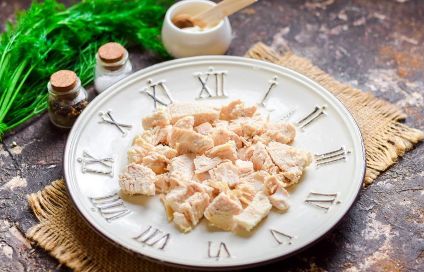 1. Этап. Салат с киви: Возьмите тарелку для салата. Вареное куриное филе нарежьте небольшими кусочками и переложите в салат - это будет первый слой.