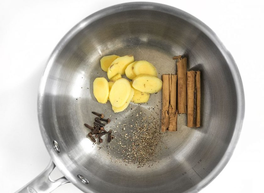 1. Этап. Чай с молоком и специями: 1. Очистите корень имбиря и нарежьте его ломтиками, выложите в сотейник, добавьте к нему корицу, молотый перец, гвоздику.