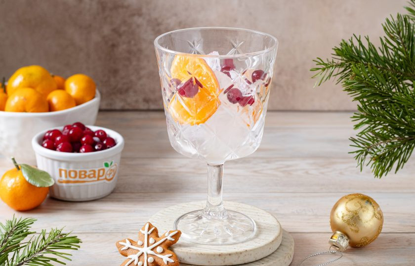 1. Этап. Новогодний коктейль: В бокал выложите лед. Добавьте клюкву и пару кружочков мандарина.