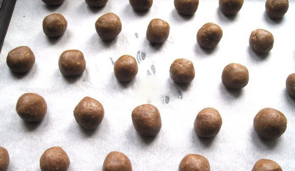 1. Этап. Рождественское печенье со специями: Когда тесто охладится, достаньте его из холодильника и разделите на равные части, из которых затем сформируйте шарики размером с грецкий орех. Выложите их на противень, застеленный пергаментом. Выпекайте в разогретой до ста семидесяти градусов духовке двадцать минут. В процессе запекания шарики расползутся и станут похожи на полусферы.