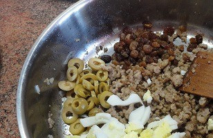 1. Этап. Слоеные пирожки с мясом Эмпанадас: Яйца отварить вкрутую и мелко порубить. Оливки нарезать кольцами. Изюм промыть, отжать воду. Все добавить в фарш.