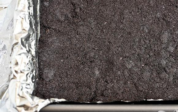 1. Этап. Шоколадные пирожные со сливочной начинкой: 3. Выложить полученную массу в подготовленную форму, разровнять поверхность пальцами. Запекать в течение 10 минут, затем дать остыть, пока вы готовите начинку. Оставшееся печенье поместить в кухонный комбайн и измельчить до консистенции крошки.