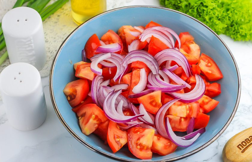1. Этап. Салат из помидоров с соевым соусом: Очистите и промойте красный лук вместе с зеленым. Нарежьте красный лук полукольцами и добавьте к помидорам.