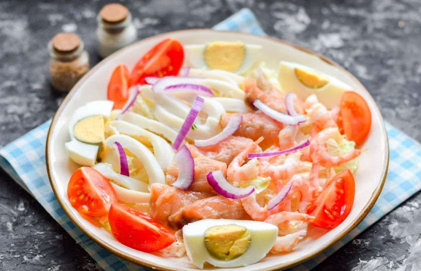 1. Этап. Салат из пекинской капусты с морепродуктами: Добавьте в салат вареное яйцо, нарезанное дольками, томаты черри и немного красного лука. Слегка сбрызните морепродукты лимонным соком.