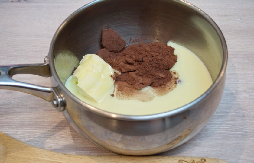 1. Этап. Шоколадная колбаса: В сотейник поместите сахарную пудру (можно взять и обычный сахар, но тогда готовую шоколадную массу нужно дольше держать на огне, чтобы сахар растворился). Добавьте сгущенное молоко, сливочное масло и какао. Растопите все на паровой бане, помешивая. Если вы используете такой сотейник, как у меня (толстостенный), то можно ставить его сразу на небольшой огонь.