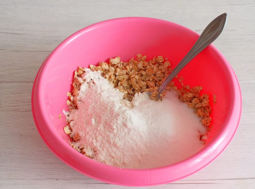 1. Этап. Шведское овсяное печенье: Добавьте муку, сахар, ванилин и разрыхлитель. Перемешайте руками. Консистенция будет рассыпчатой, схожей с мокрым песком.