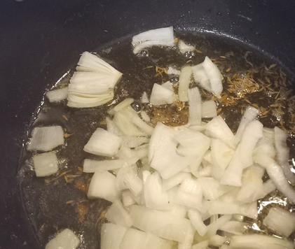 1. Этап. Карри из картофеля и зелёного горошка: В том же казане на среднем огне разогреть оставшиеся 3 столовых ложки сливочного масла. Готовить зиру в течение одной минуты. Затем добавить лук и готовить до размягчения 8-9 минут.