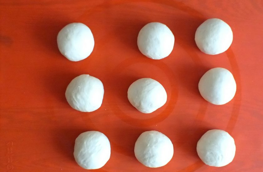 1. Этап. Ватрушки с бананом: По истечении времени, не обминая тесто, разделите его на 9 частей. В среднем вес заготовки каждой 50 грамм. Округлите их.