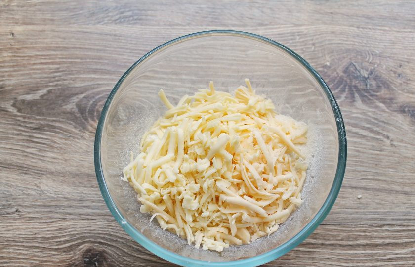 1. Этап. Сырные булочки без дрожжей: Сыр натрите на крупной терке и добавьте к муке.