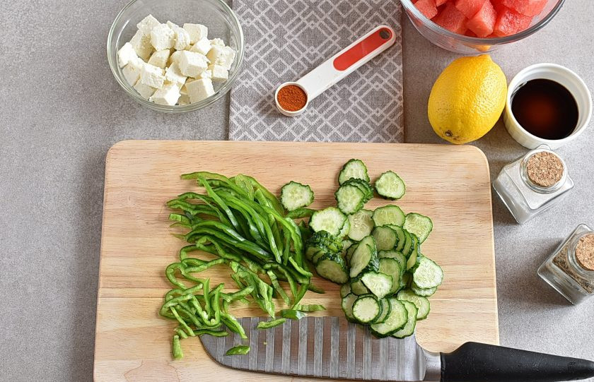 1. Этап. Салат из арбуза: Продукты лучше брать прямо из холодильника. Тонко нашинкуйте огурец и сладкий перец. Перемешайте и выложите в салатник.