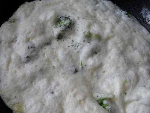 1. Этап. Омлет с брокколи на сковороде: Влейте молочную смесь на сковороду к брокколи, готовьте 3 минуты под крышкой.