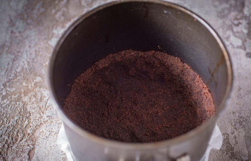 1. Этап. Шоколадный чизкейк с выпечкой: Дно разъемной формы застелите пергаментом для выпекания, выложите всю песочную массу, руками утрамбуйте, формируя основу для будущего чизкейка с бортиками высотой примерно в 5-6 см. Отправьте основу в уже разогретую до 180 градусов духовку на 10 минут.