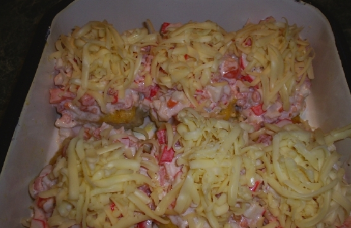 1. Этап. Рыба, запеченная с крабовыми палочками: Получившейся смесью покрываем рыбу, а сверху присыпаем тертым сыром. Запекаем блюдо в духовке до румяной корочки.