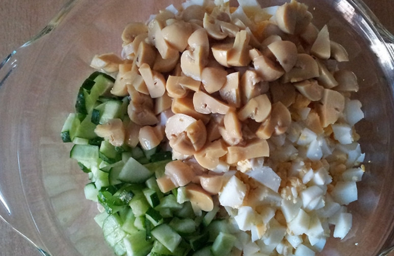 1. Этап. Салат с консервированными шампиньонами: Маринованные шампиньоны нарежьте половинками или четвертинками. Добавьте в салатницу.