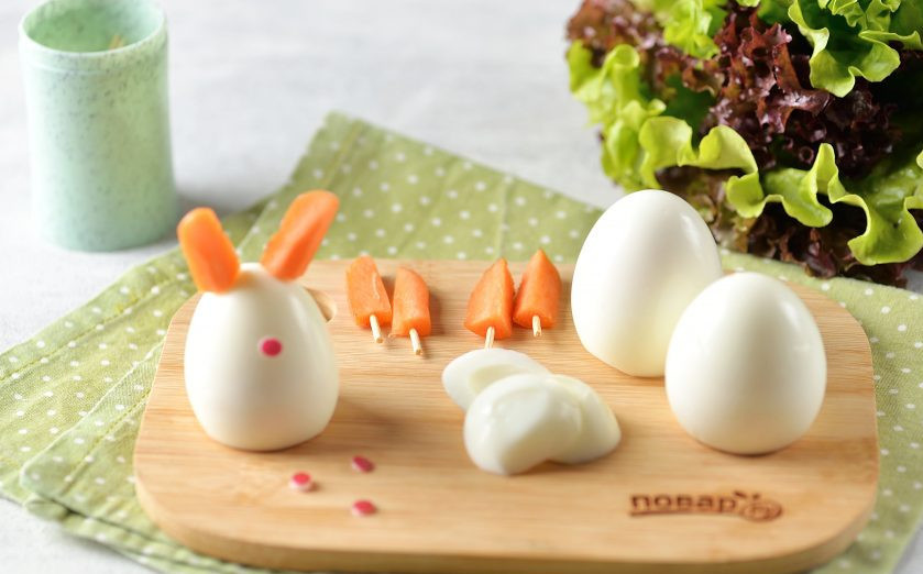 1. Этап. Новогодний завтрак Веселый кролик: Слегка подрежьте яйца внизу, чтобы они хорошо стояли на плоской поверхности. Приклейте носик из редиса, вставьте ушки.