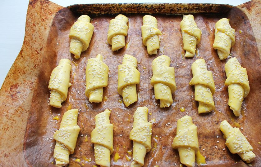 1. Этап. Рогалики в хлебопечке: Выложите рогалики на противень застеленный бумагой для выпечки или ковриком для выпечки. Яйцо размешайте и смажьте, посыпьте каждый кунжутом.