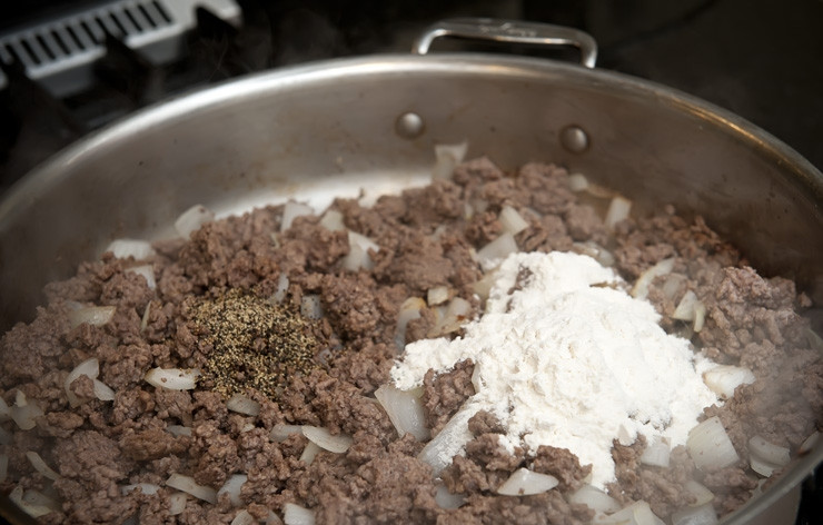 1. Этап. Пастуший пирог: Щедро посыпаем черным молотым перцем и добавляем муку. Хорошенько размешиваем, пока вся она не впитается.