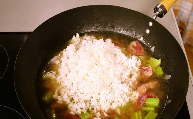 1. Этап. Говядина по-испански: Теперь выкладываем заранее отваренный до полуготовности рис и заливаем все содержимое сковороды бульоном.