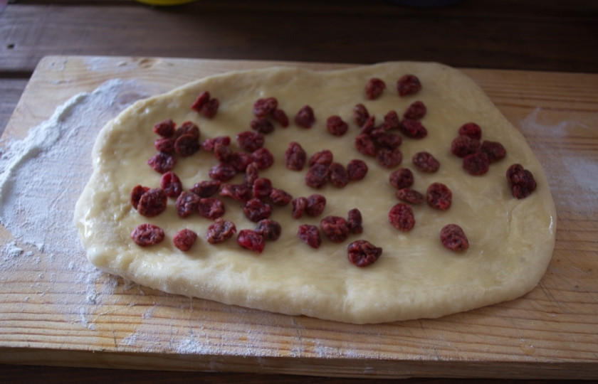 1. Этап. Сладкие булочки на кефире: Выложите вяленую вишню. Сверните тесто в рулет.