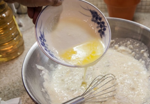 1. Этап. Оладьи на топленом молоке: Растопите масло и влейте в тесто, хорошо все перемешайте.