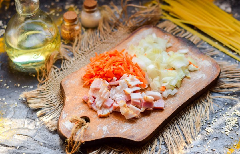 1. Этап. Суп с лапшой и капустой: Нарежьте мелко бекон, очистите овощи. Морковь натрите стружкой, лук нарежьте небольшими кубиками.